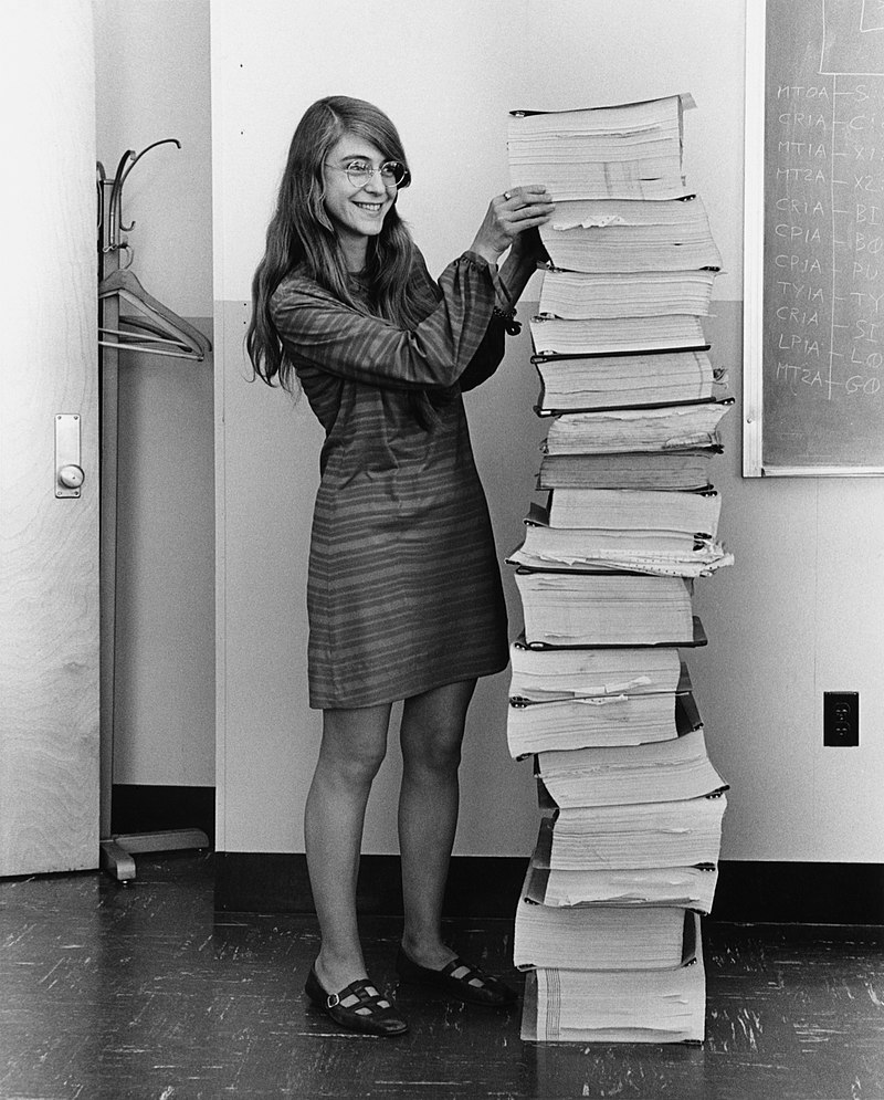 Margaret Hamilton in 1969, standing next to listings of the software she and her MIT team produced for the Apollo project, public domain[1].